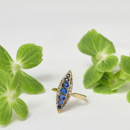 ANILLO LANZADERA ANTIGUO DE ORO AMARILLO CON VISTAS DE PLATINO, CON UNA FILA DE ZAFIROS Y DIAMANTES EN LOS LATERALES